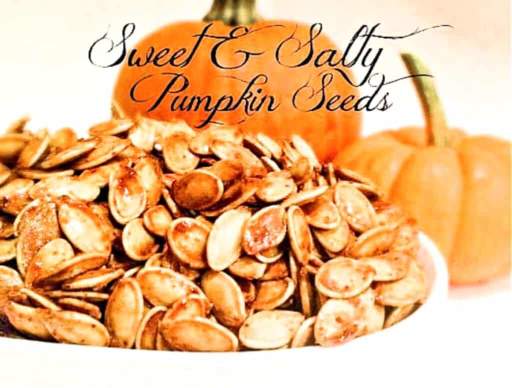 A bowl filled with Sweet and Salty Pumpkin Seeds sits in front of two whole pumpkins. Decorative script above the bowl reads “Sweet & Salty Pumpkin Seeds.”.