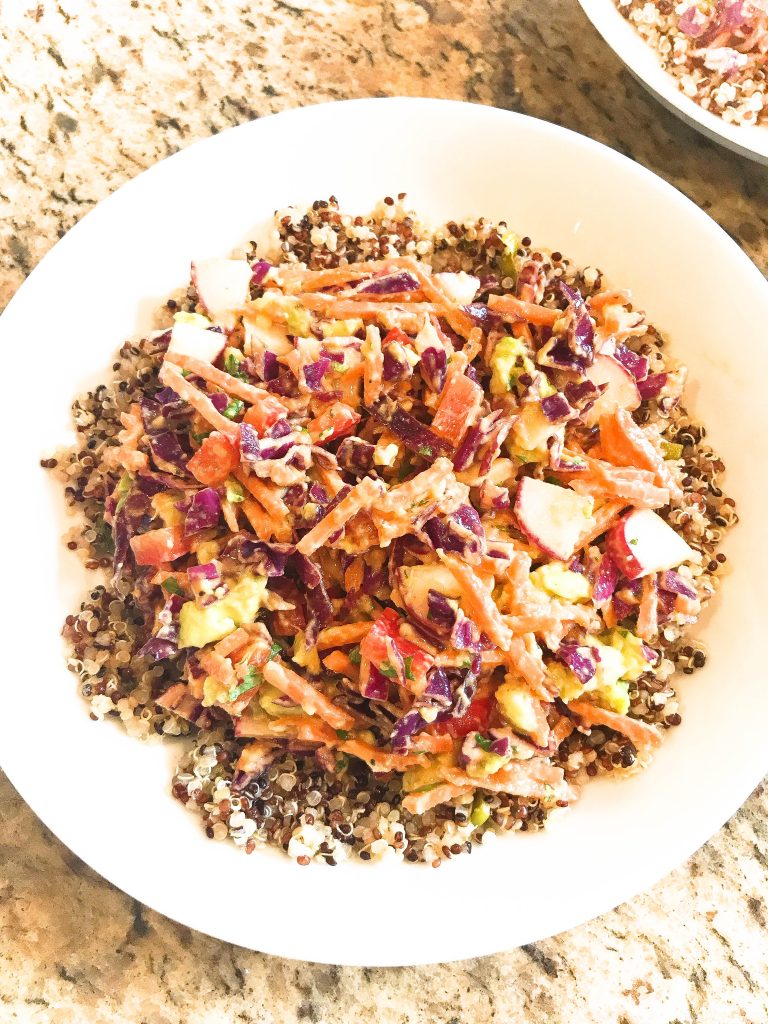 Vegan Red Curry Quinoa Salad - Tri-color quinoa piled with cabbage, carrots, red bell pepper, radishes, scallions, and avocado tossed in red curry sauce.