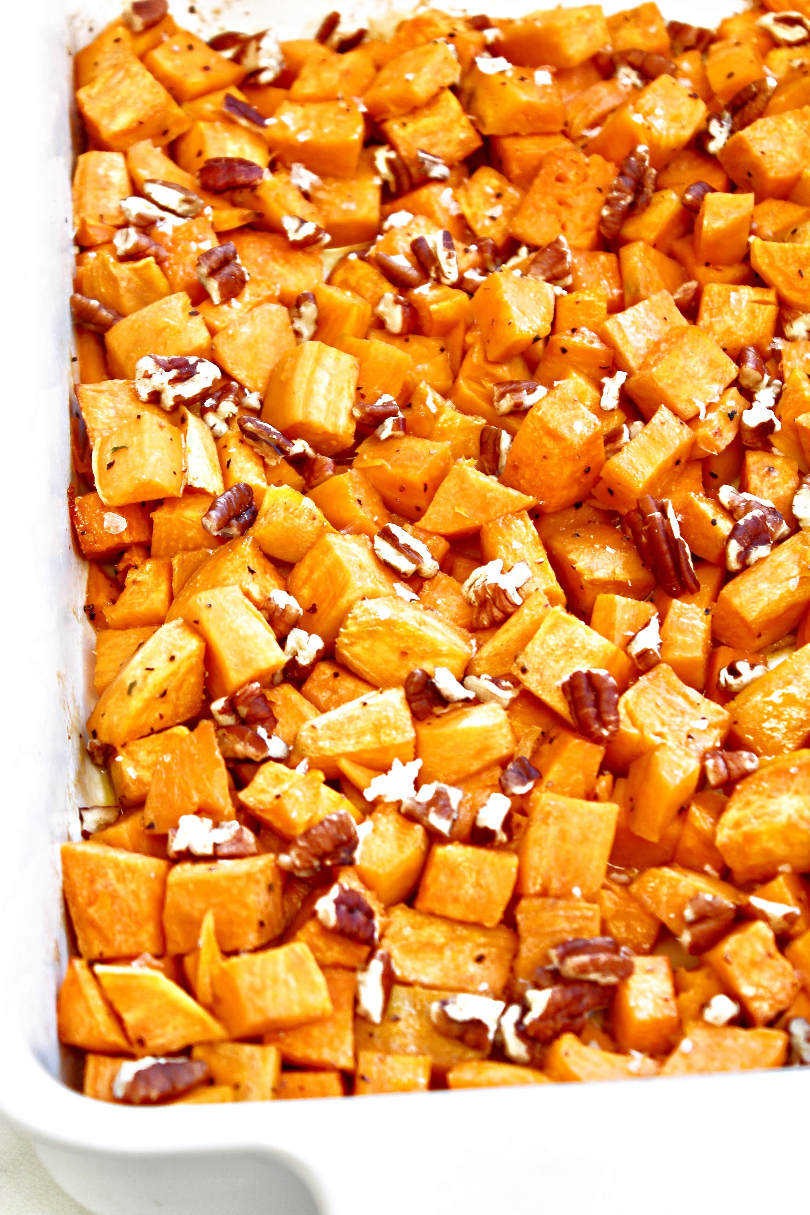 Roasted Sweet Potatoes ~ Bite-site chunks of sweet potatoes roasted with olive oil and maple syrup are lightly crisp on the outside and soft on the inside. Sea salt, ground black pepper, and toasted pecans add savory balance to this naturally sweet fall seasonal favorite. Ready to serve in under an hour and make an easy and flavorful side dish for Thanksgiving or Christmas dinner.