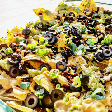 Beefy Black Bean Nachos ~ Easy to make and always a crowd-pleaser! These loaded vegan nachos drizzled with dairy-free Green Chile Queso are perfect for game day snacking.
