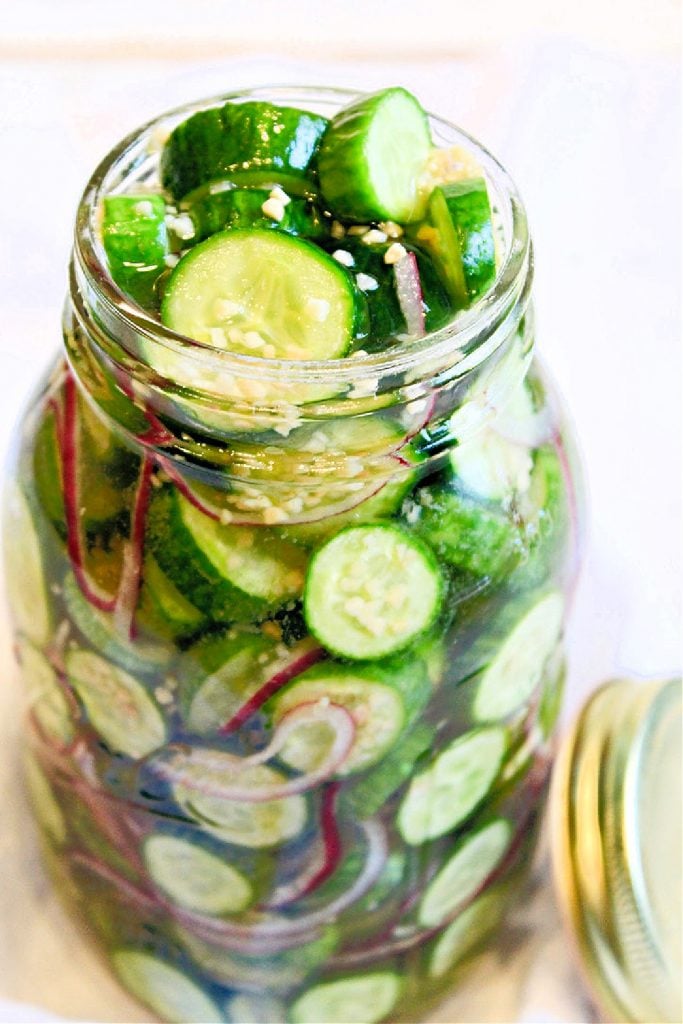 View of glass jar filled with refrigerator pickle ingredients.