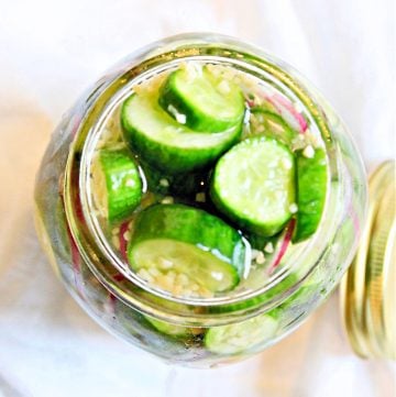 Top down view of glass jar filled with ingredients for refrigerator pickles.