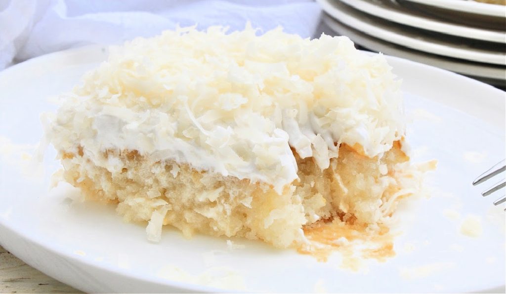 Vegan Coconut Poke Cake ~ Classic white cake infused with tropical coconut flavor then topped with coconut whipped cream and shredded coconut. Perfect for summer entertaining!