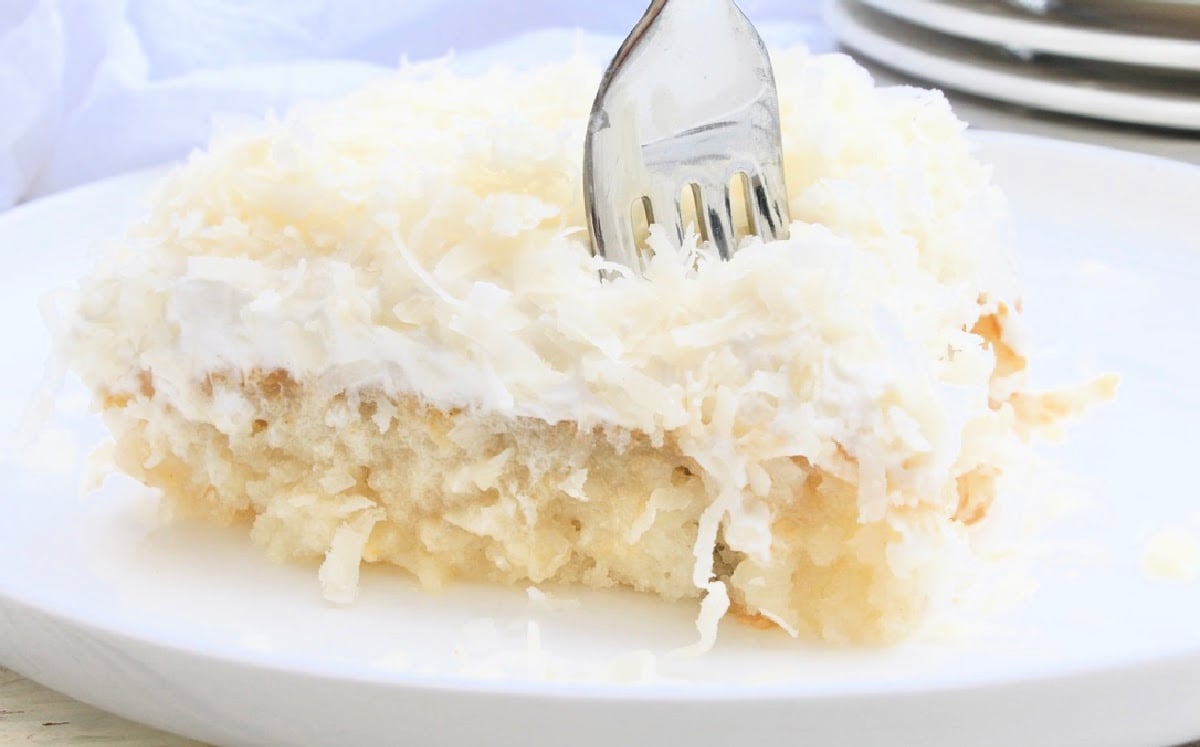 Vegan Coconut Poke Cake ~ Classic white cake infused with tropical coconut flavor then topped with coconut whipped cream and shredded coconut. Perfect for summer entertaining!