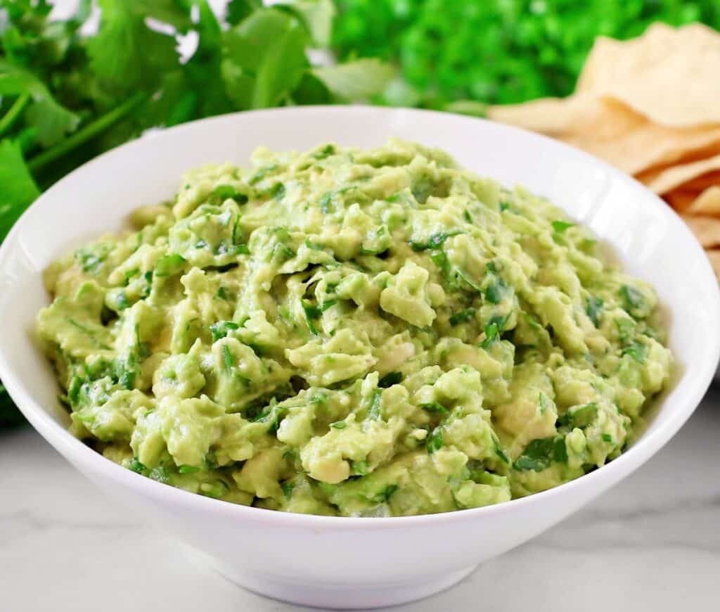 Cilantro Lime Guacamole Dip Recipe - Ripe avocados, fresh cilantro, onion, simple seasonings, and lime juice combine to create authentic guacamole in minutes.