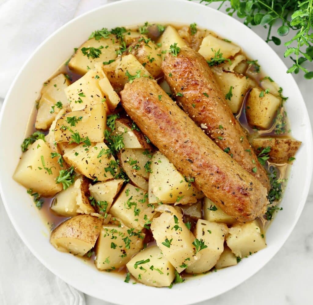 A bowl of Dublin Coddle, a hearty Irish stew made with plant-based sausages, potatoes, and a rich, savory Guinness broth.