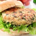 A close-up of a veggie burger with a chickpea patty, fresh green leaf lettuce, and a soft hamburger bun. The patty is lightly browned and speckled with herbs.