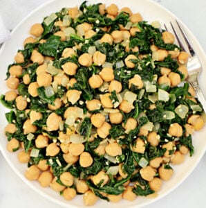 A plate of sautéed spinach, chickpeas, and diced onions is served with a fork on the side. The dish appears light and healthy, featuring green and beige colors.