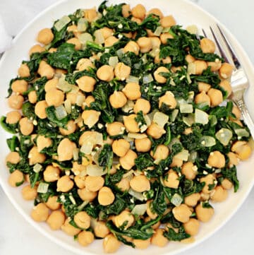 A plate of sautéed spinach, chickpeas, and diced onions is served with a fork on the side. The dish appears light and healthy, featuring green and beige colors.