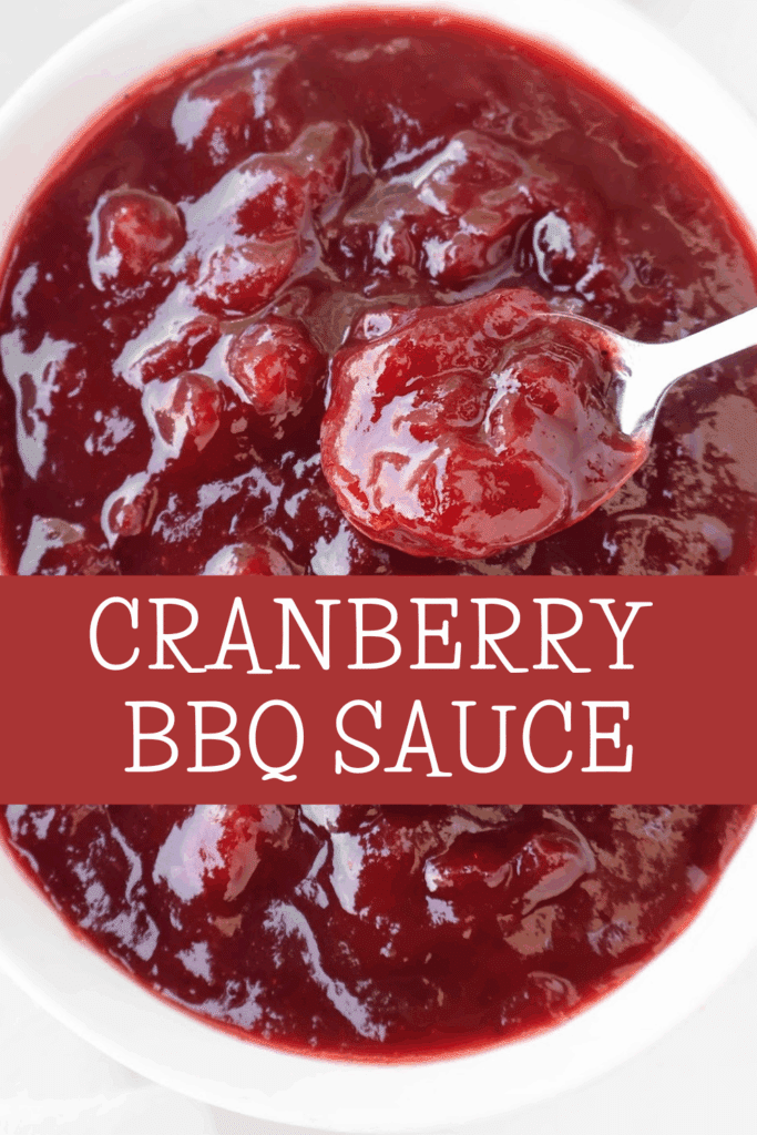 A close-up of a bowl filled with thick, chunky cranberry BBQ sauce, with a spoon lifting a portion. Text across the image reads Cranberry BBQ Sauce.