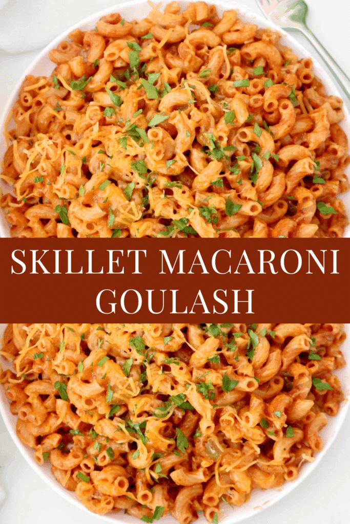 A close-up of skillet American goulash, macaroni topped with melted cheese and chopped parsley, served on a white plate with a fork. Text across the image reads: Skillet Macaroni Goulash.